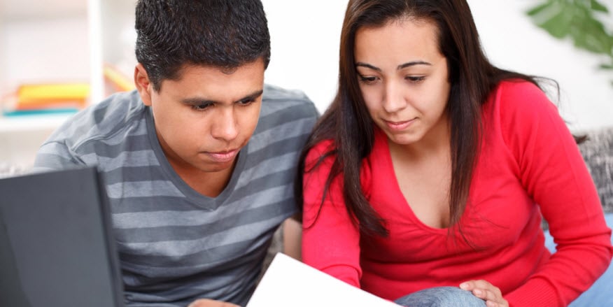 Hispanic couple looking at a paper and laptop