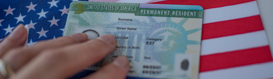 Permanent Resident Green card of United states of America on flag of USA. Above close up view